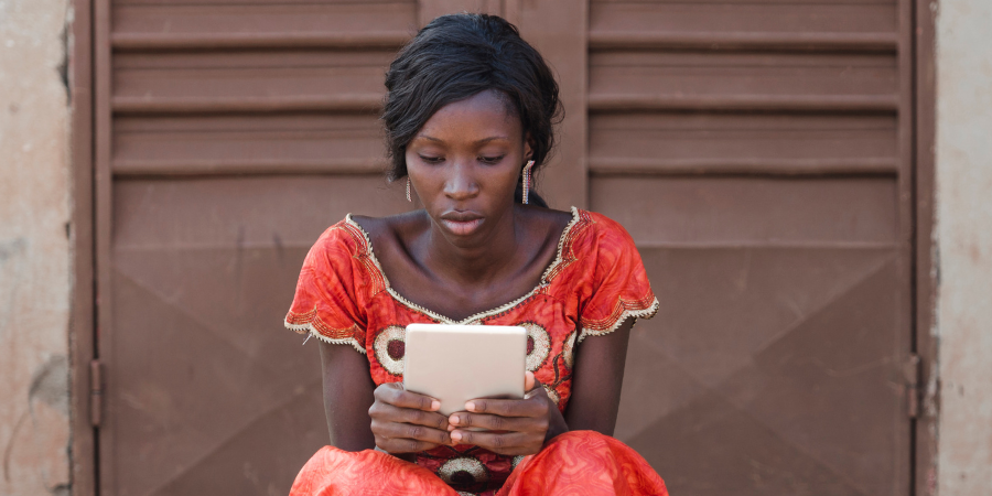 Street Shot of an African young woman working on business holding her tablet in a university in Bamako, Mali
