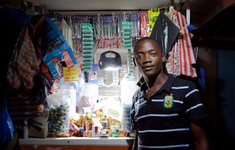 African man in shop, using solar lighting, d.light