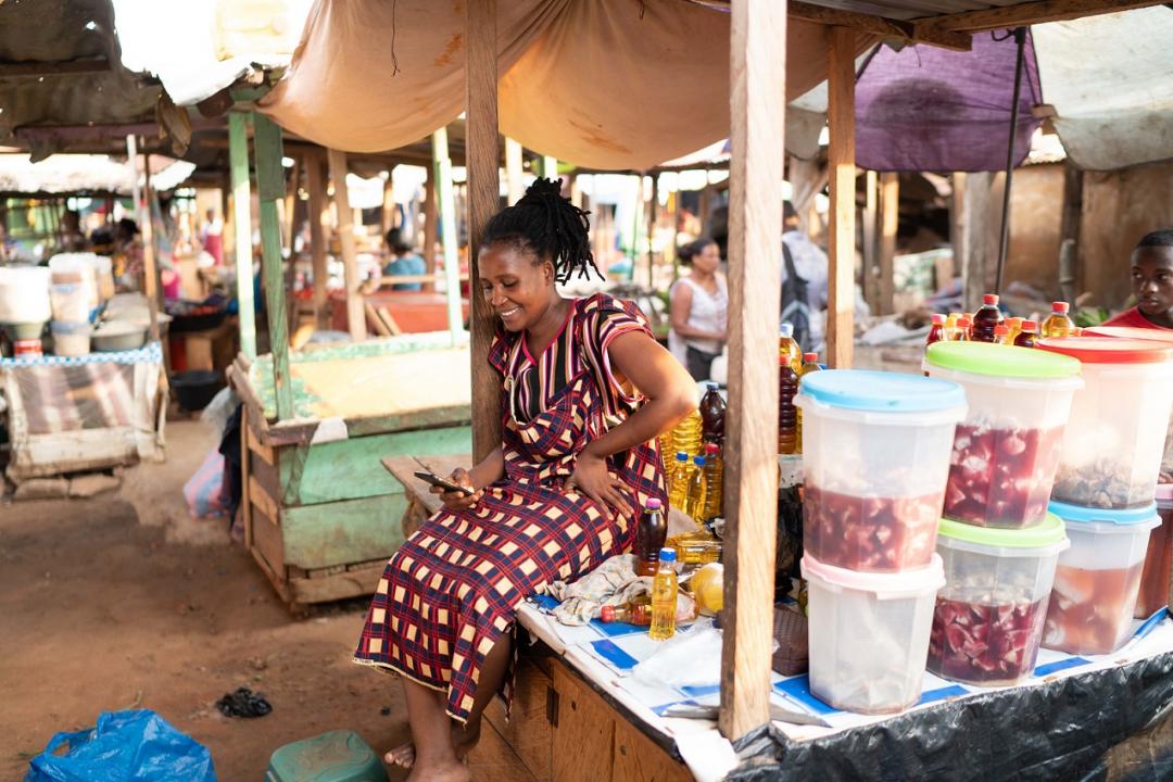 an African woman checking her phone in a market